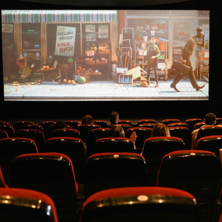 A cozy indoor movie theater showing an animated film to a small audience.