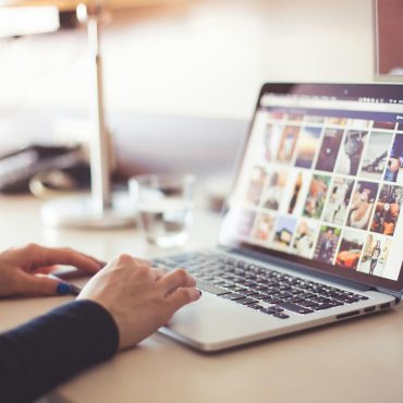 Close-up of hands typing on a laptop with an image gallery open on the screen.